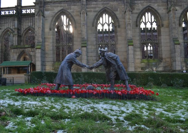 a statue of two people shaking hands in front of a building