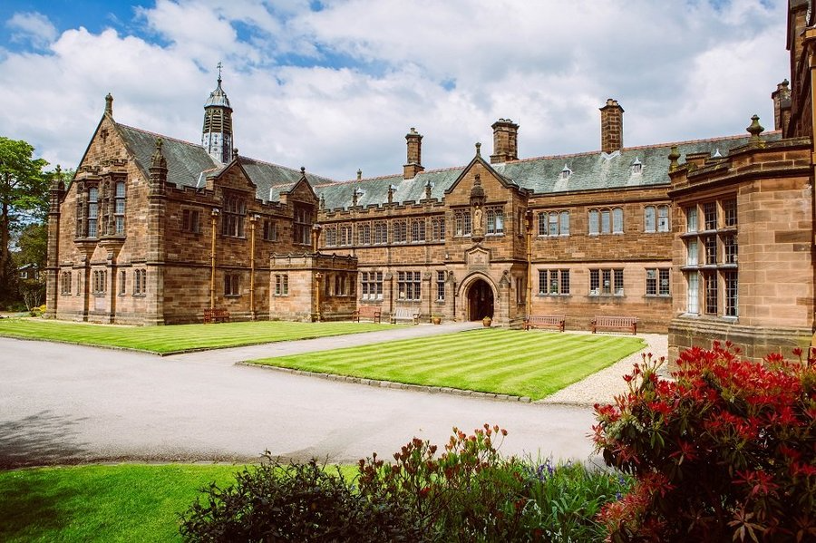 A large building surrounded by a well-maintained lawn and a vibrant garden